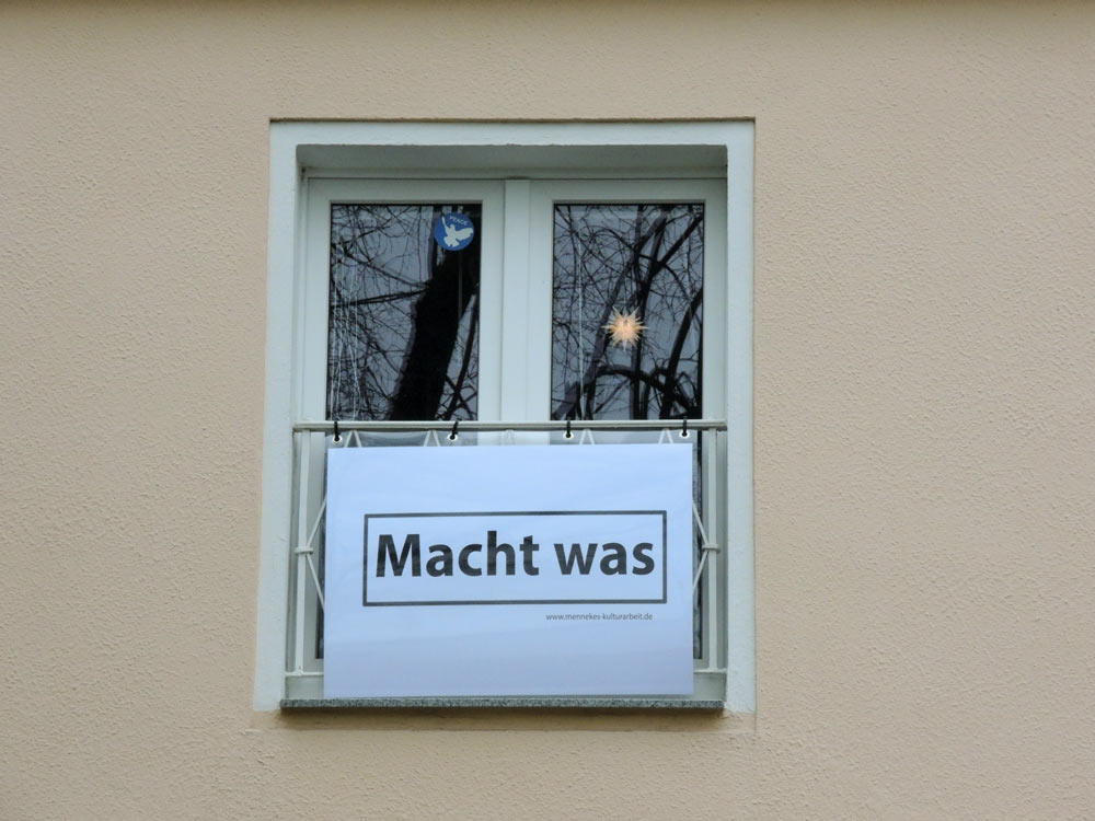 Fensterpräsentation an der Hausfassade. Gezeigt werden im Wechsel zeitaktuelle Plakate, Texte und Bildmotive.